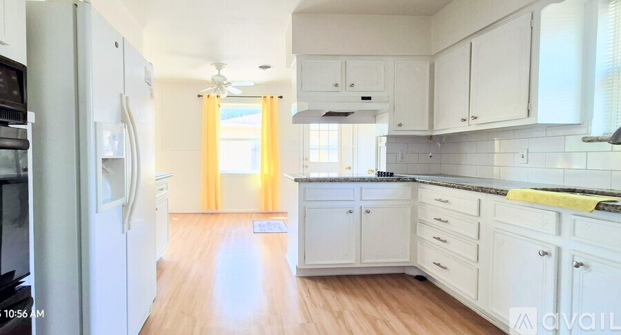 A kitchen with white cabinets and a black fridge.