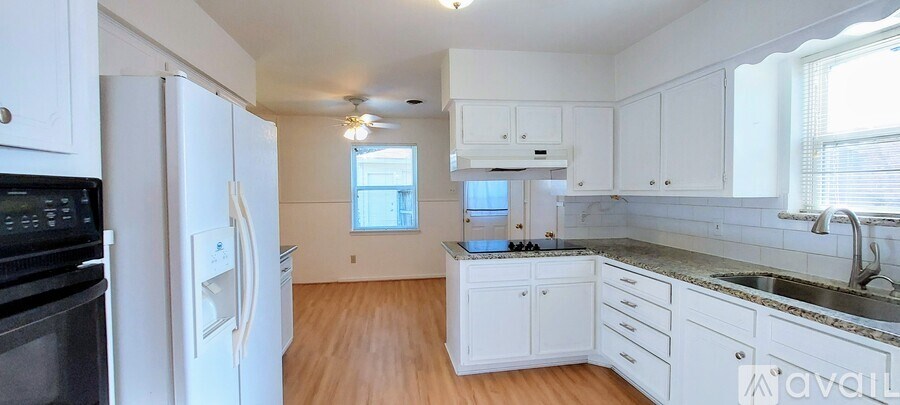 A kitchen with white cabinets and a black fridge.