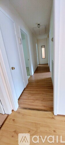 A long hallway with wooden floors and white walls.