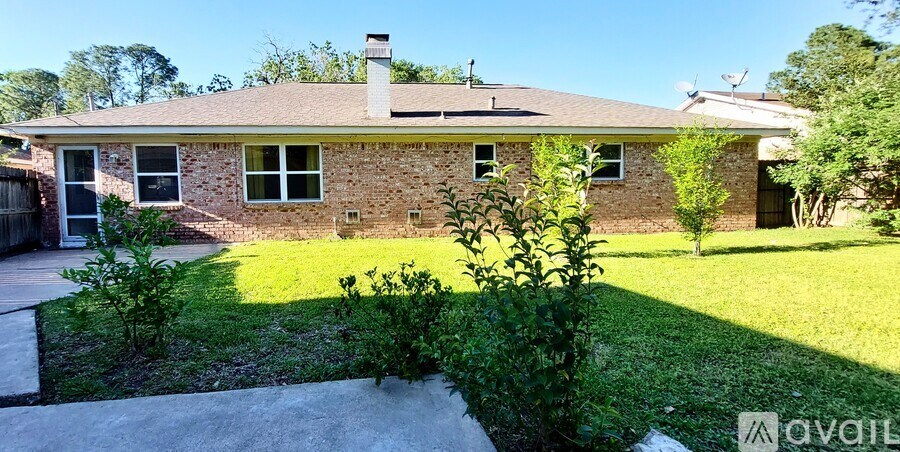 A house with a brick exterior and a chimney is surrounded by a well-kept lawn and a small garden.