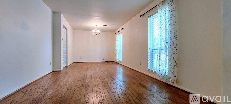 A room with wooden floors and a window with curtains.