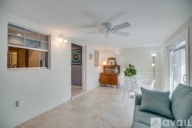 A living room with a grey couch and a ceiling fan.