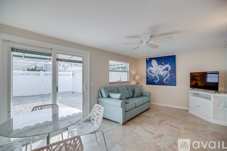 A living room with a television, a couch, a chair, a dining table, and a ceiling fan.