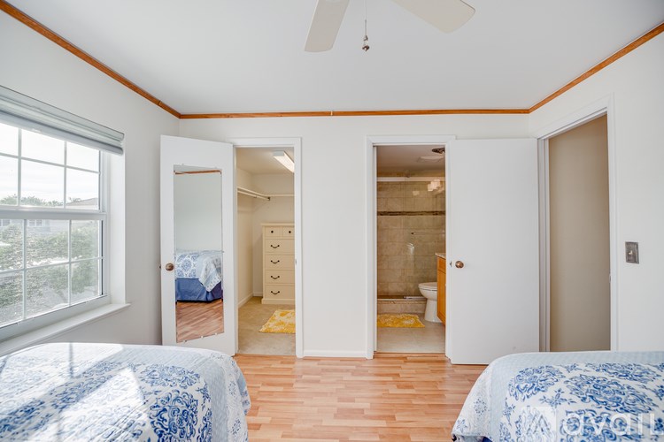 A bedroom with two beds and a ceiling fan.