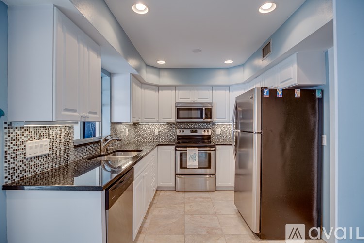 A kitchen with a black refrigerator and a tiled backsplash.