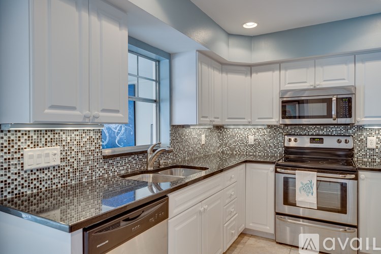 A kitchen with white cabinets and a black and white tiled backsplash.