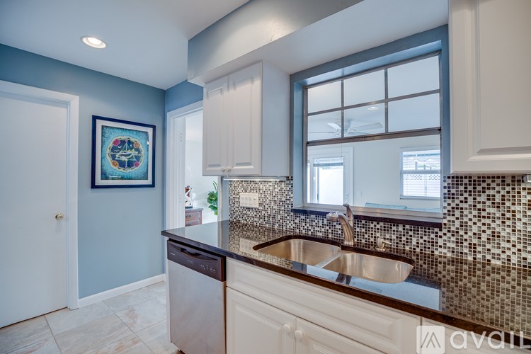 A kitchen with a blue wall and a framed picture above the sink.