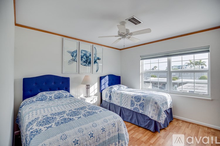 Two twin beds with blue and white bedspreads in a room with a ceiling fan.