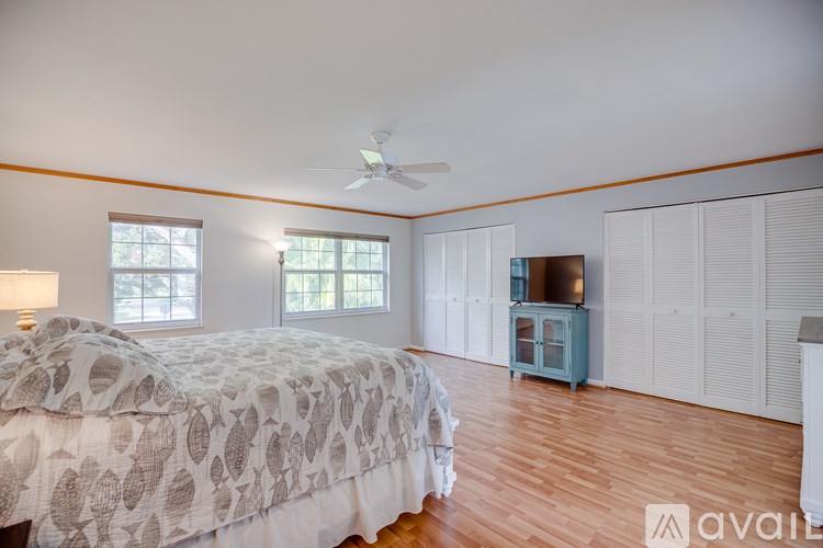 A bedroom with a bed, a ceiling fan, and a cabinet.