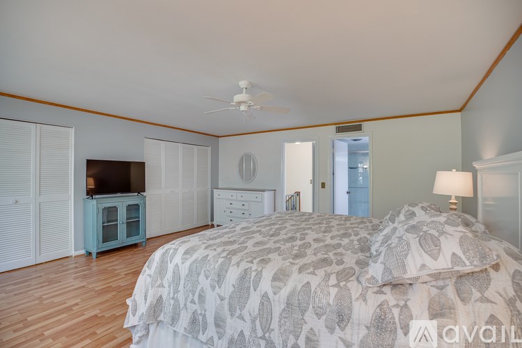 A bedroom with a large bed and a ceiling fan.