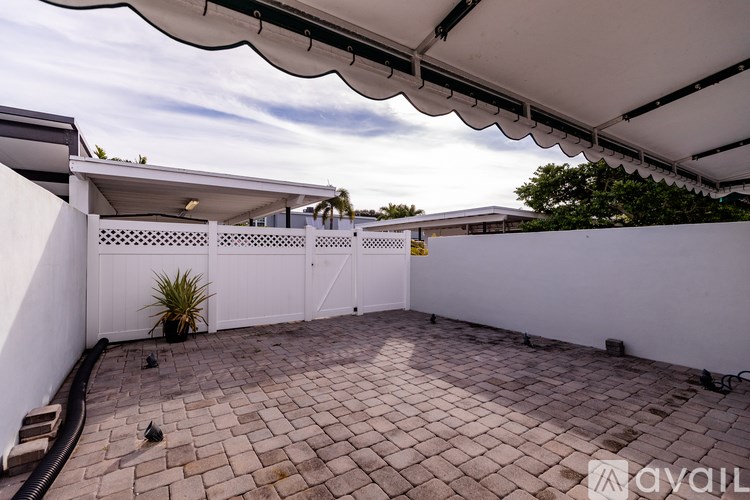 A patio area with a white pergola and a brick floor.
