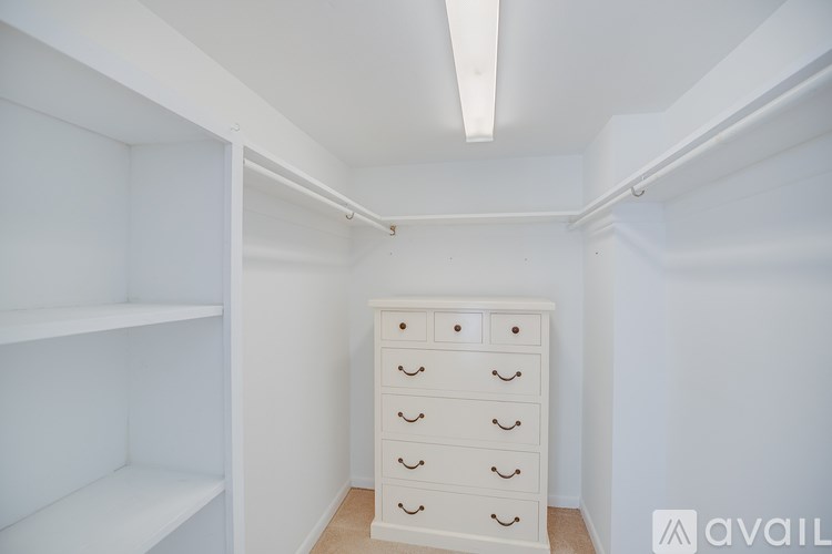 A white chest of drawers in a room with white walls.