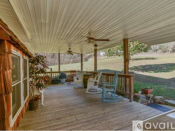 A wooden deck with chairs and a ceiling fan.