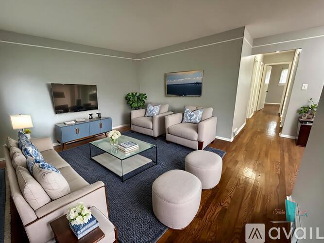 A living room with a glass coffee table and a blue rug.