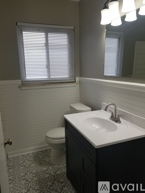 A bathroom with a toilet, sink, and window.