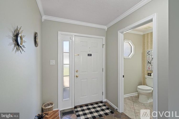 A bathroom with a white door and a mirror on the wall.