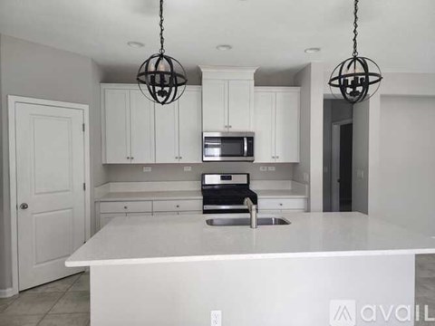 A kitchen with white cabinets and a white island.