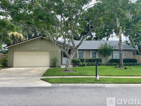A house with a garage and a tree in front of it.