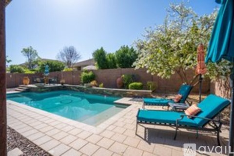 A pool with a blue umbrella and two lounge chairs.