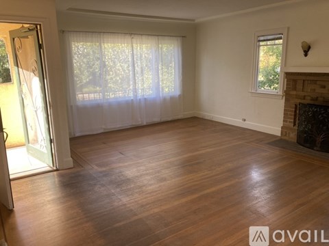 A room with wooden flooring and a fireplace.
