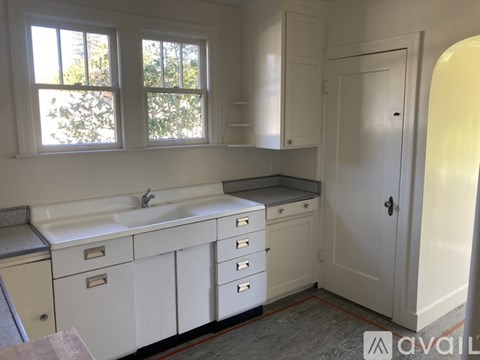 A white kitchen with a sink and a window.