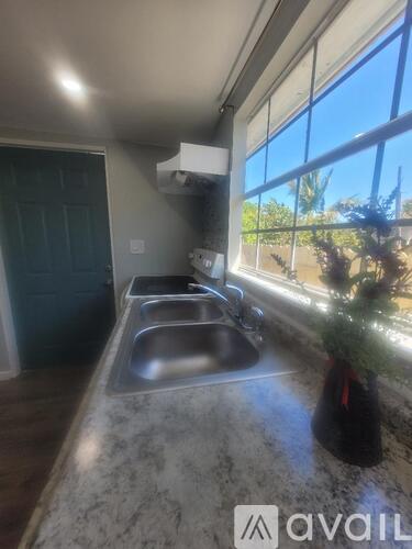 A kitchen with a marble countertop and a window overlooking a tree.
