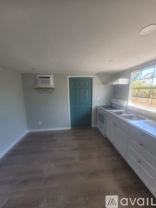 A room with a blue door and a window with a view of trees outside.
