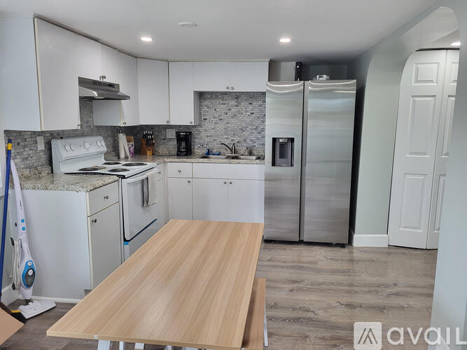 A kitchen with white appliances and a wooden table.