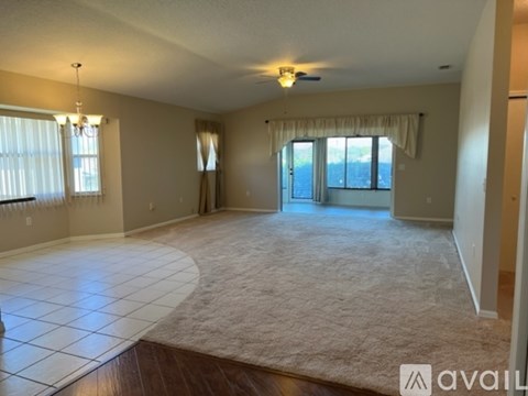 A spacious living room with a large rug and a window with curtains.