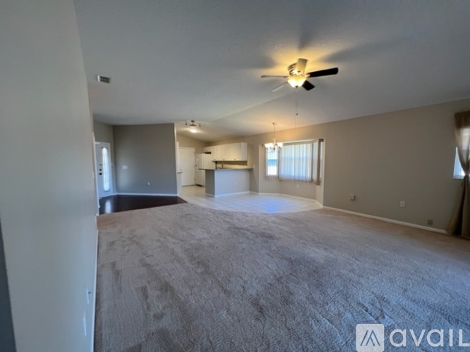 A spacious room with a carpeted floor and a ceiling fan.