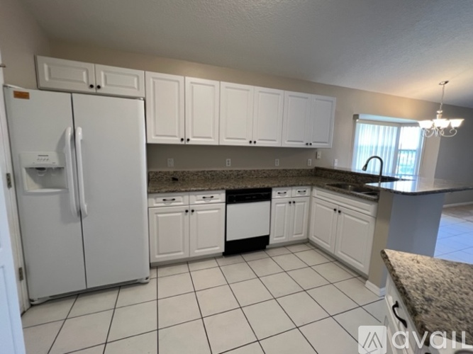 A kitchen with white cabinets and a granite countertop.