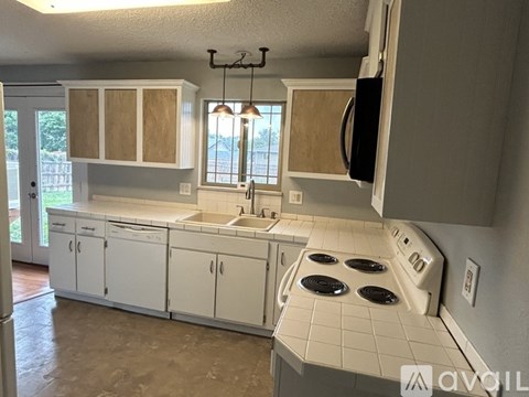 A kitchen with white cabinets and a tiled stove top.