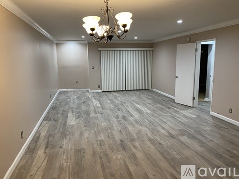 A room with wooden flooring and a chandelier.