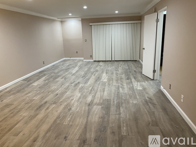 A spacious room with wooden flooring and a sliding door.