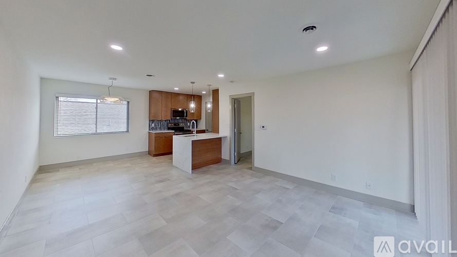 A spacious room with a kitchenette and a window with blinds.