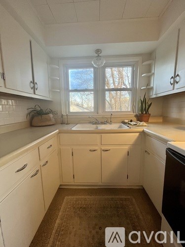 A kitchen with white cabinets and a brown rug.