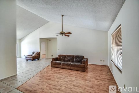 A living room with a brown couch and a ceiling fan.