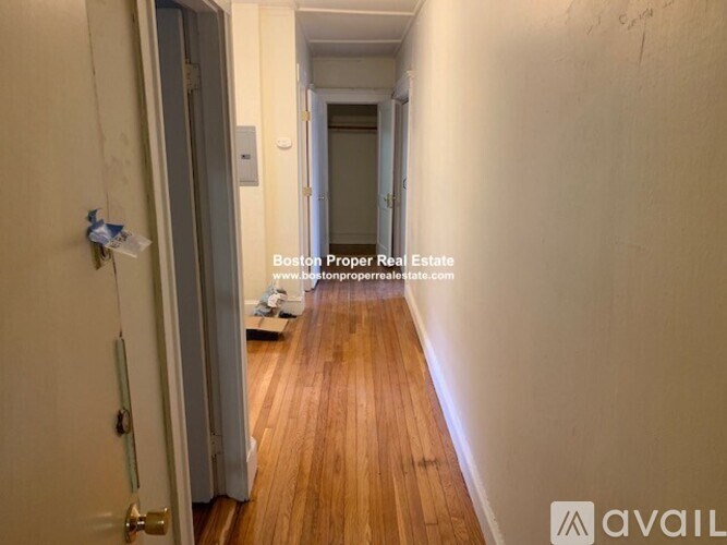 A hallway with wooden floors and white walls.