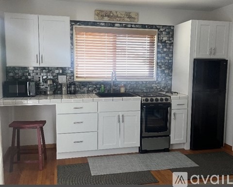 A kitchen with white cabinets and a black refrigerator.