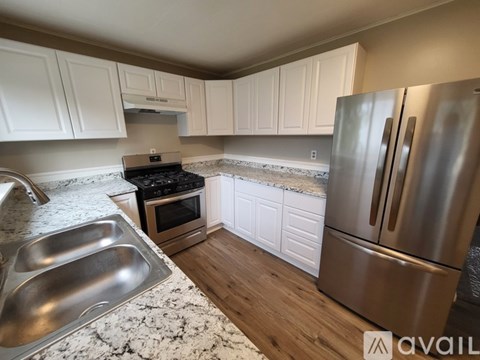 A kitchen with white cabinets and a stainless steel refrigerator.
