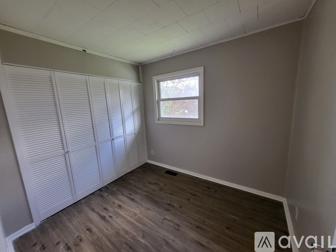A room with a window and wooden flooring.