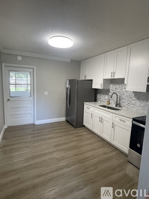 A kitchen with white cabinets and a wooden floor.