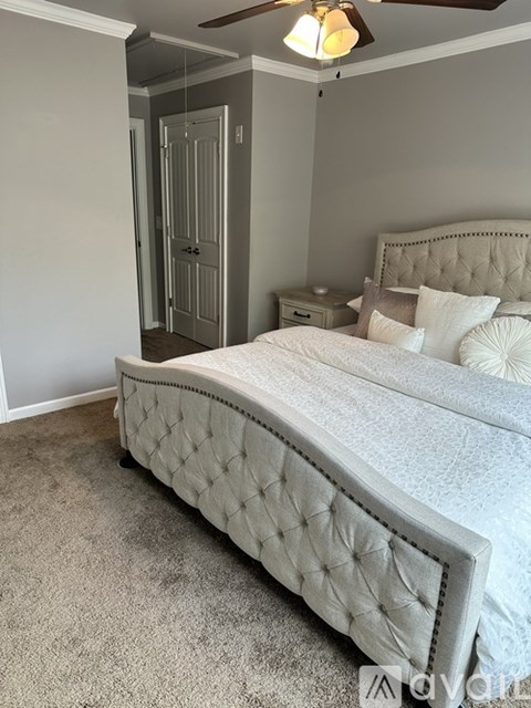 A bedroom with a large bed and a ceiling fan.