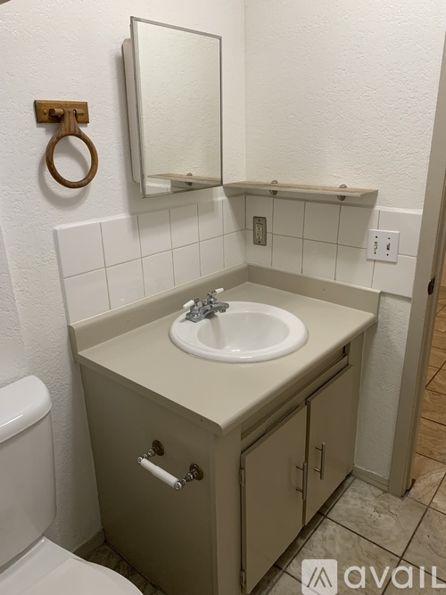 A bathroom with a toilet, sink, and mirror.