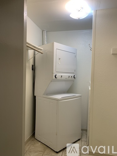 A white industrial-sized washing machine in a narrow room.