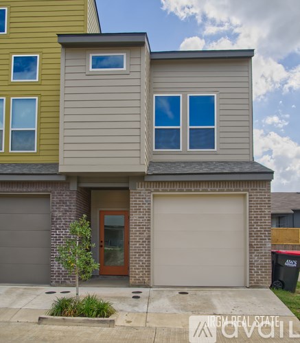 A two-story house with a garage door and a brown door.