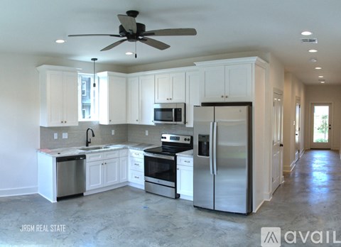A kitchen with white cabinets and stainless steel appliances is available for rent.