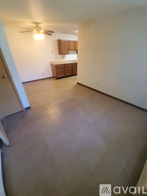 A room with a ceiling fan and a kitchenette.