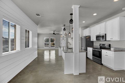 A spacious kitchen with white cabinets and a marble countertop.