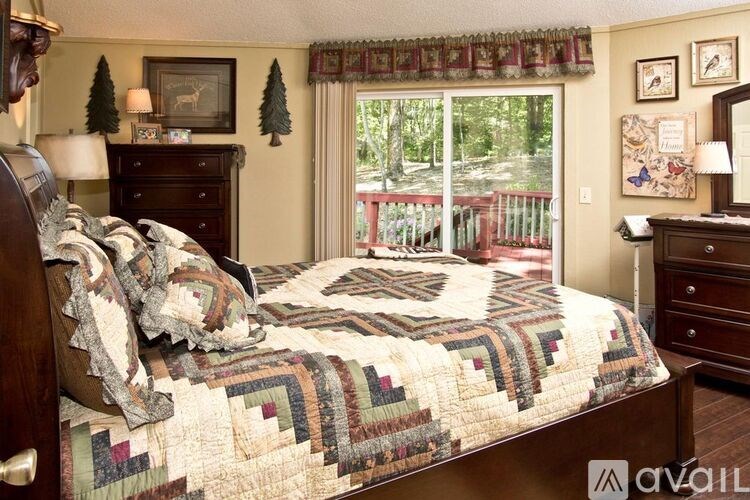 A bedroom with a large bed and a view of a deck outside the window.